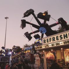 an amusement park at dusk with people standing around and riding the rides on roller coasters