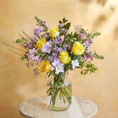 a vase filled with yellow and purple flowers