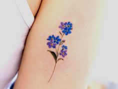 a small blue flower tattoo on the back of a woman's arm