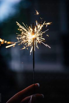 a person holding a sparkler in their hand with the light turned on by an individual's hand