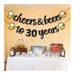 a table topped with lots of bottles and glasses next to a sign that says cheers to 30 years