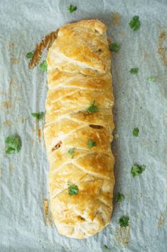 a piece of bread sitting on top of a white paper covered in parsley and cilantro