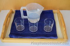 three glasses and a pitcher are sitting on a tray with a blue towel in front of it