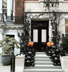 an entrance to a building decorated with pumpkins and black pots in front of it