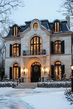 a large white house with lots of windows and lights on it's front door