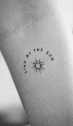 a woman's arm with the words live by the sun tattooed on her left side