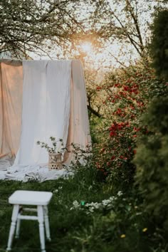 a white chair sitting in the middle of a lush green field