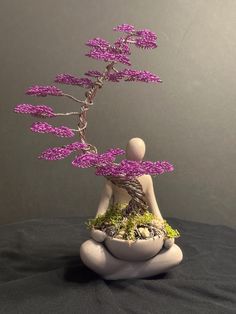 a small bonsai tree with purple flowers in it