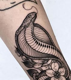 a black and white photo of a snake on someone's leg with flowers around it