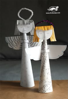 two paper angel standing next to each other