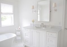 a white bathroom with two sinks and a bathtub