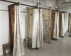 an empty room with curtains hanging from the ceiling and a bench in front of it