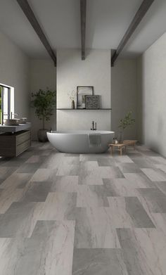 a bathroom with a tub, sink and large tile flooring in grey tones on the walls