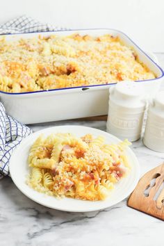 a white plate topped with pasta next to a casserole dish