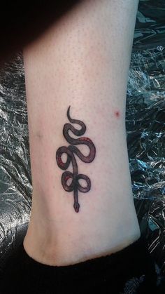 a black and white tattoo on the foot of a person with a snake in it