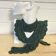 a crocheted green scarf on a white mannequin's head and neck