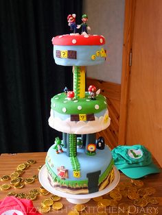 a three tiered cake with mario and luigi's house on top, surrounded by gold coins