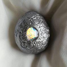 a rock sitting on top of a white sheet covered in water droplets and an opalite