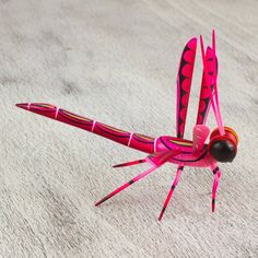 a pink dragonfly sitting on top of a white carpet