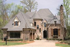 a large brick house with lots of windows on the front and side of it's roof