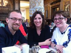 two women and a man sitting at a table with coffee cups in front of them