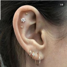 a woman wearing three different ear piercings on her left ear and the other two are gold