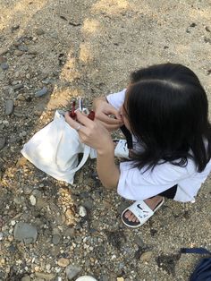 a woman sitting on the ground holding an apple in her hand and looking at it