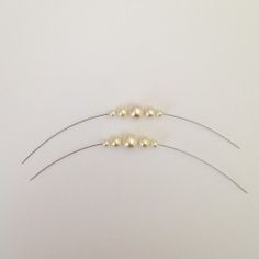 three white pearls are attached to the back of a headband with two silver pins