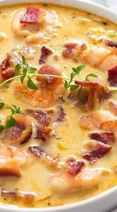 a close up of a bowl of soup with shrimp and bacon in it on a table