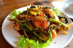 a white plate topped with meat and veggies on top of a wooden table