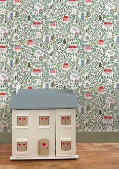 a white doll house sitting on top of a wooden floor next to a wallpaper