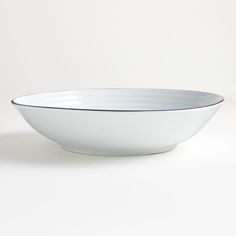 a white bowl with blue rim on a white surface, ready to be used as a serving dish