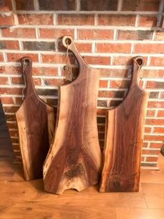 three wooden cutting boards sitting on top of a table next to a brick wall and potted plant