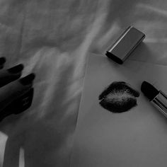 black and white photograph of lipstick, pen and paper