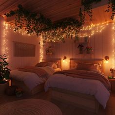 two beds in a room with lights on the wall and plants growing over them,