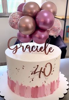 a white cake with pink and gold balloons on top that says gracelle forty years