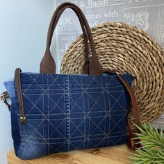 a blue purse sitting on top of a wooden table next to a basket and plant