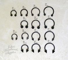 twelve pairs of black metal nose rings with an arrow on each side and the names of them