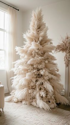 a white christmas tree sitting in the middle of a living room next to a window