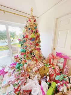 a decorated christmas tree in a room with lots of presents on the floor next to it