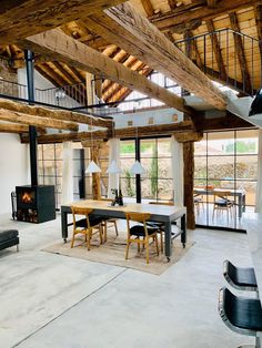 an open living room and dining area with exposed wood beams, white walls and flooring