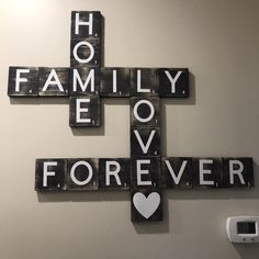 a cross made out of scrabble tiles that says family love forever