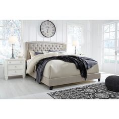 a bedroom with white furniture and a large clock on the wall above the headboard