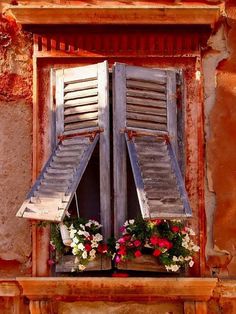 an old window with shutters and flower boxes