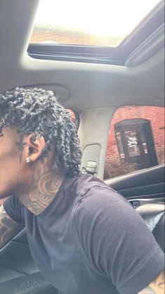 a man with dreadlocks sitting in the driver's seat of a car