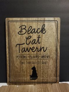 a wooden plaque with the words black cat tavern on it and an image of a cat