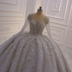 a wedding dress on display in front of a mannequin head and white wall