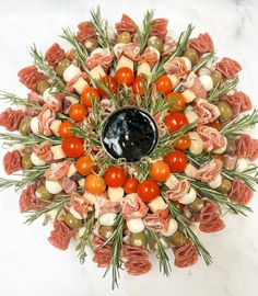 an arrangement of meats and vegetables arranged in the shape of a circle on a marble surface