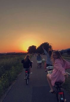 several children riding bikes down a road at sunset