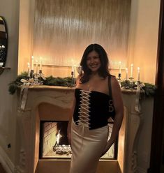 a woman standing in front of a fire place wearing a corset and skirt